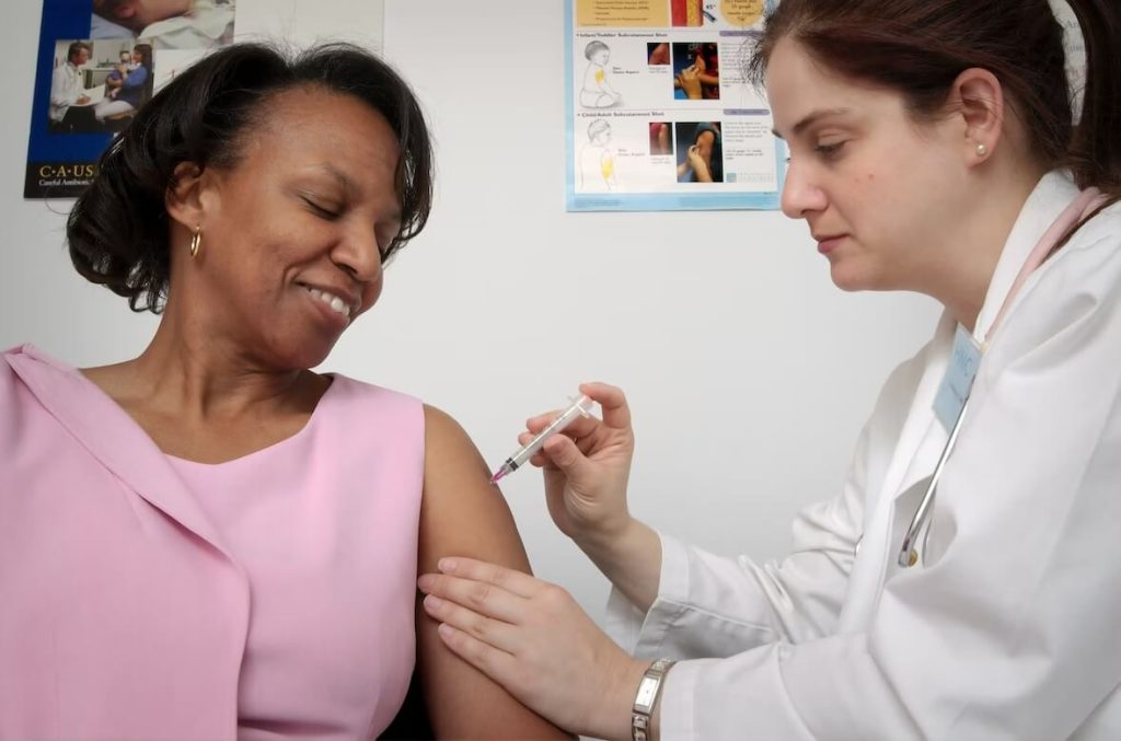 Woman receiving an injection from a doctor, highlighting anti-aging treatment options in a clinical setting.