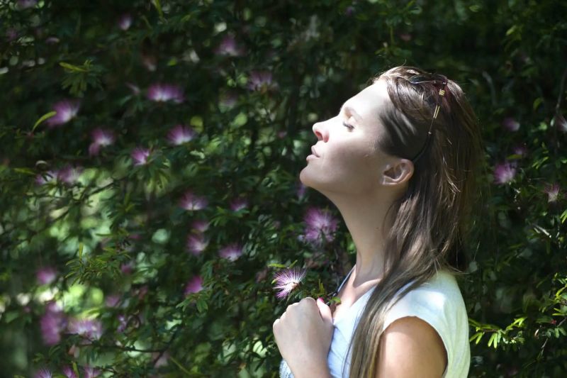 Woman enjoying fresh air and sunlight in a lush green setting, symbolizing relief and emotional well-being, relevant to ketamine infusion therapy for mental health.