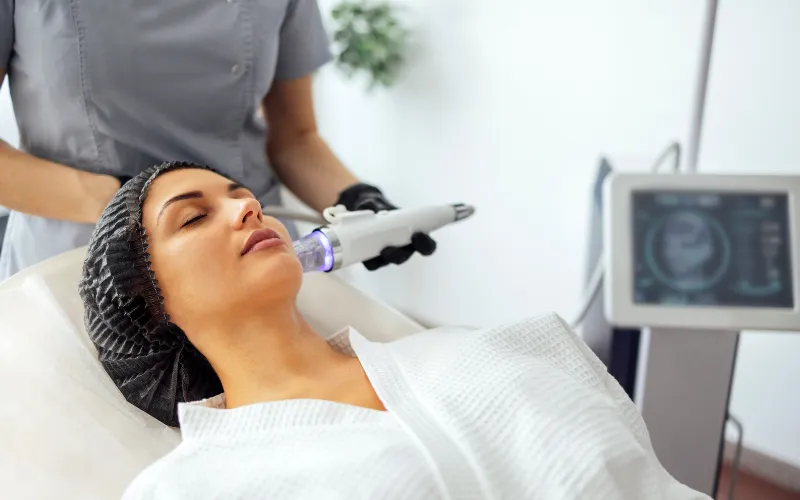 Woman receiving Morpheus 8 treatment for skin rejuvenation, with a practitioner using a handheld device in a clinical setting.